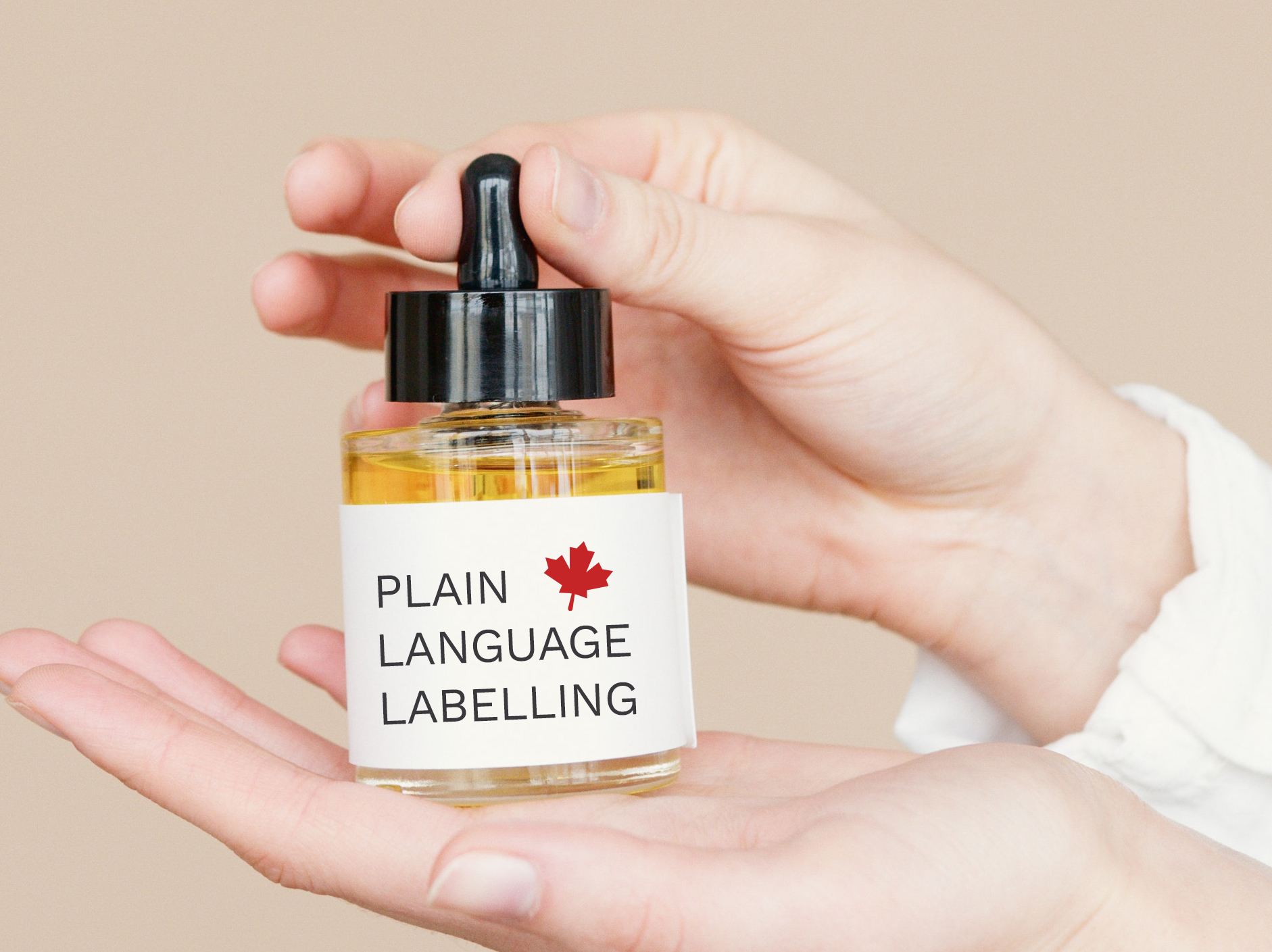 Photograph of someone holding a dropper bottle of oil with "Plain language labelling" written on it and a Canadian Maple Leaf