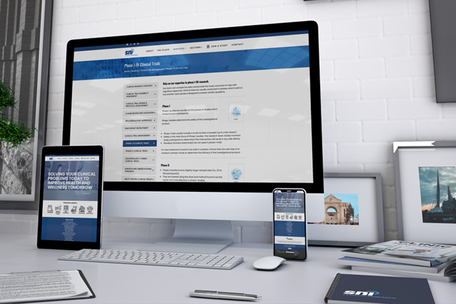 An office desk in Winnipeg that shows how the new SNIclinic.com website looks on a desktop computer, a tablet and a smartphone.