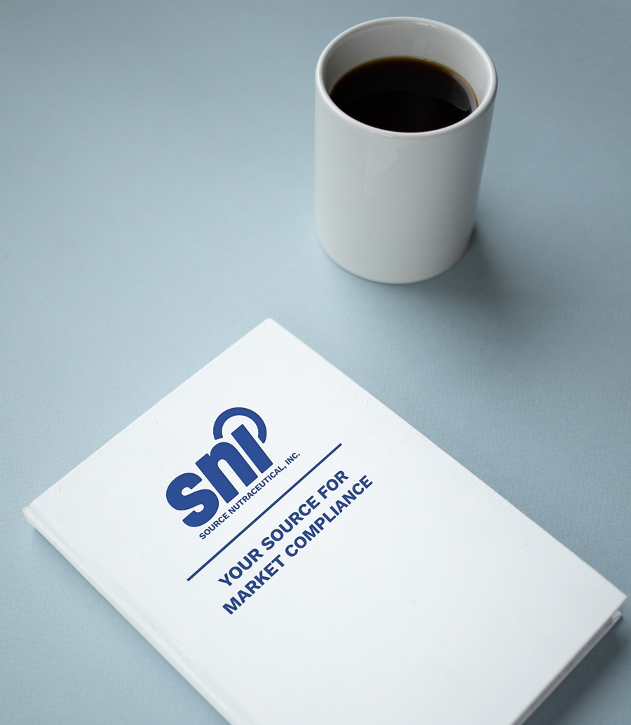 Photograph of a notebook with SNI logo and slogan next to a hot cup of coffee.