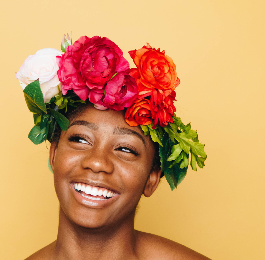 Photograph of a smiling, glowing woman with natural flowers on her head