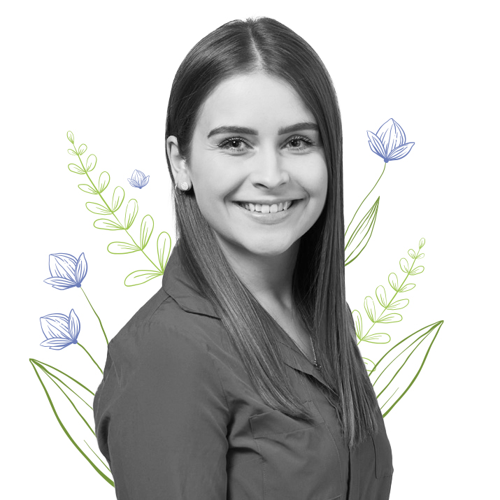 Photograph of Alexis Goosen, Graphic Designer flanked by some leaves and purple, stemmed flowers