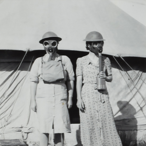 two woman in a vintage photo wearing gas masks