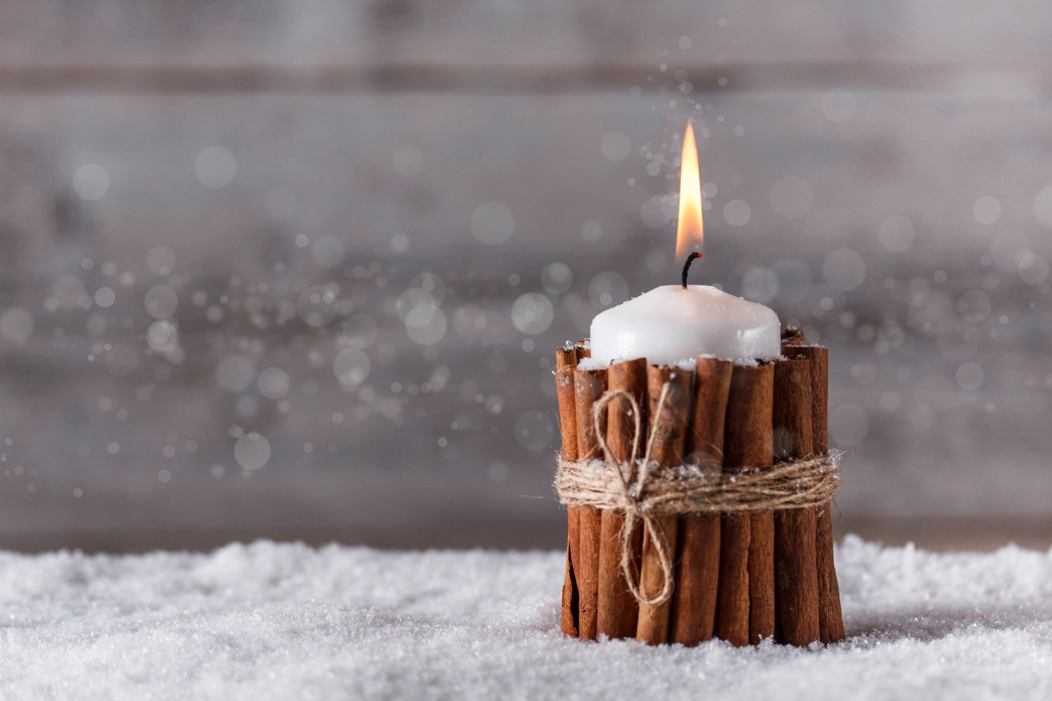 A cinnamon-stick-wrapped candle in the snow