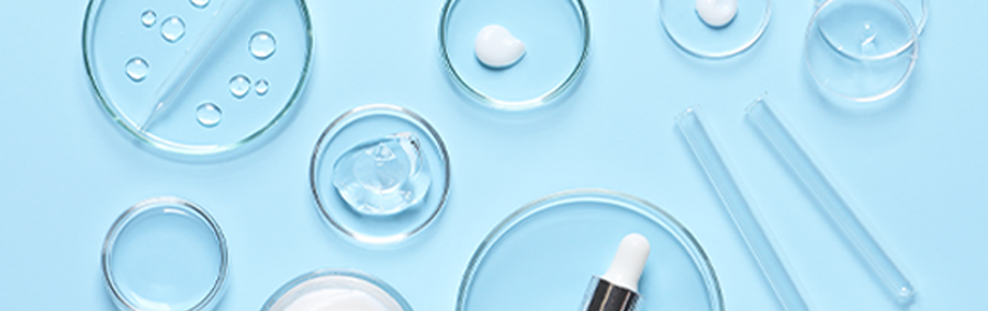 various clean glass cosmetic products on a light blue surface