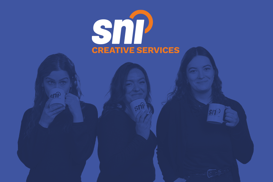 Photograph of the three team members that make up SNI Creative Services team holding SNI mugs and smiling