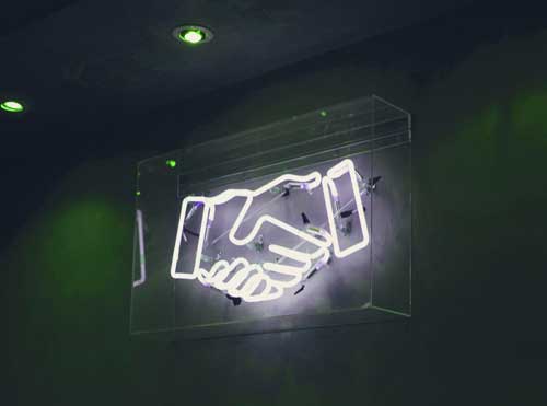 Neon sign showing two business hands shaking