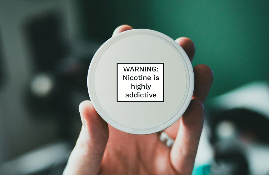 Mockup of a person holding a nicotine pouch package with the warning statement on it