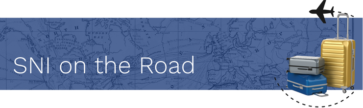 Photograph of a map with a blue overlay, some luggage and the title "SNI on the Road"